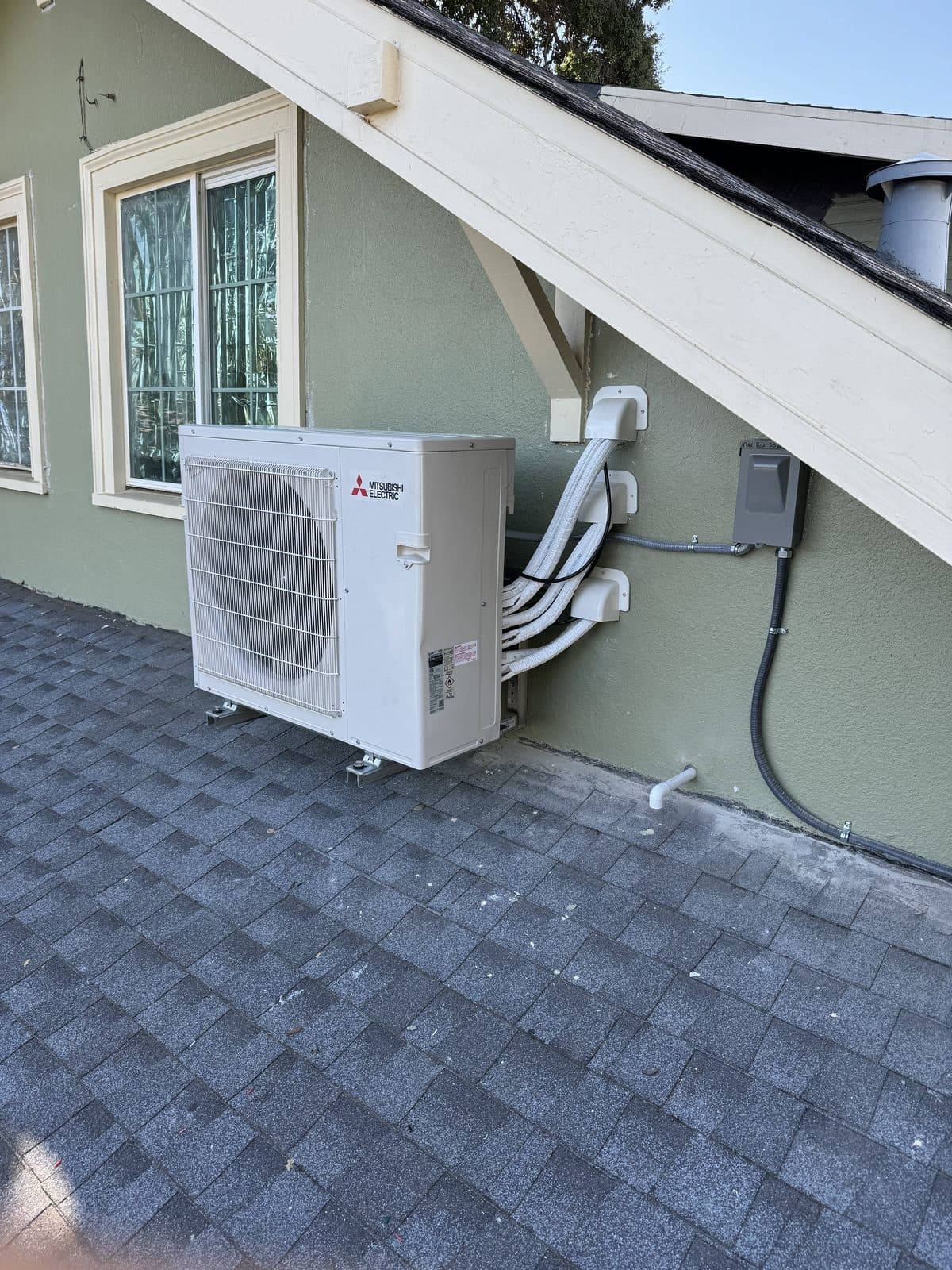 Mitsubishi mini-split outdoor condenser mounted at house exterior